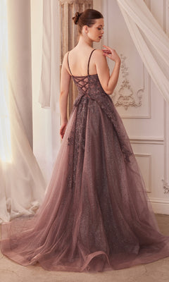 A woman stands indoors in the Sage Green Long Glitter-Tulle Prom Dress A1261, featuring a floor-length skirt and lace-up back. She faces away, her hair in a neat bun, as the shimmering sage green gown catches the light beautifully.