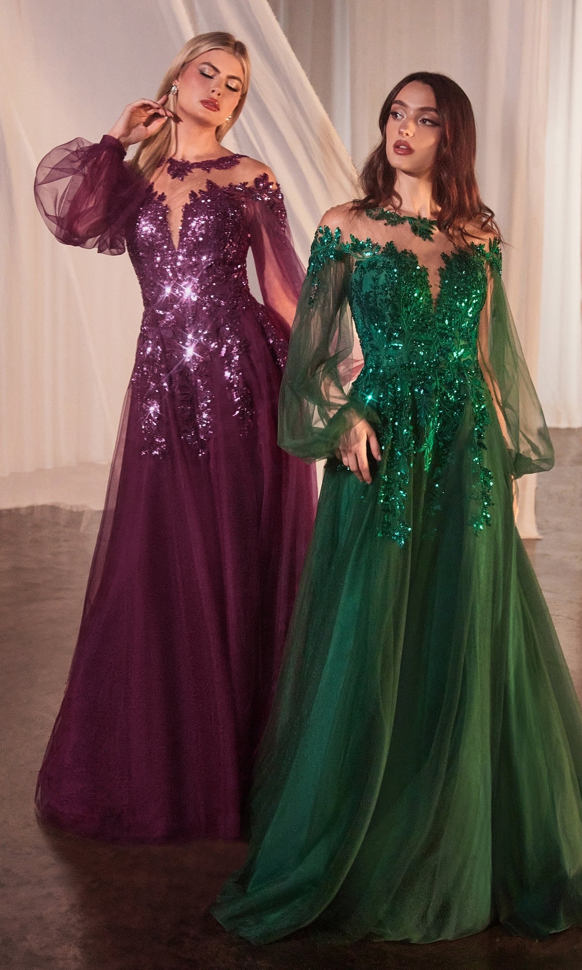 Two women stand side by side wearing the Sheer Long Sleeve Long Formal Dress A1263, one in purple and the other in green, both adorned with sequin embellishments, set against a draped fabric background.