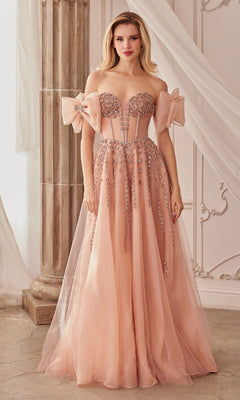 A woman stands in an elegant room wearing the Andrea and Leo A1338 strapless long prom dress, a blush pink gown adorned with sparkling beaded embellishments and tulle accents.