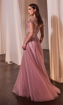 A woman in the Andrea and Leo A1350 Dusty Rose Prom Ball Gown with lace and sequin details stands on a polished floor beside sheer white curtains.