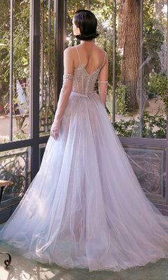 Woman with short dark hair stands indoors near large windows, wearing the Beaded Light Blue Prom Gown: Andrea and Leo A1361—an elegant floor-length dress with a fitted bodice, thin straps, and sheer gloves for a modern formal style.