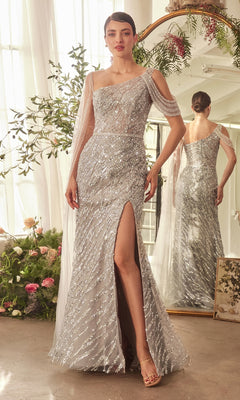 A woman in the silver Andrea & Leo A1370 long formal dress, featuring an off-the-shoulder beaded design and a thigh-high slit, stands indoors next to flowers and a mirror reflecting her back view.