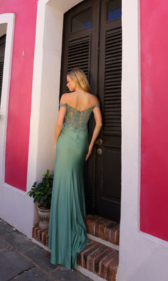 A woman stands on a small step in front of a dark door, wearing the Off-the-Shoulder Long Sweetheart Prom Dress A1373, set against a pink and white building.