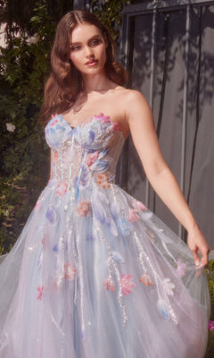 Outdoors, a woman wears the Long Strapless Prom Dress: Andrea & Leo A1383, featuring pastel floral appliqués and sheer tulle. Sunlight highlights her wavy hair and the gown’s delicate details.
