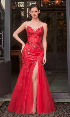 Woman wearing the Andrea & Leo A1388 strapless mermaid prom dress with floral embellishments and a thigh-high slit, standing before large glass doors.