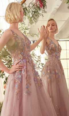 A woman in the Mauve Pink Long Prom Ball Gown (CLA1394) with floral-lace appliques stands before a mirror, touching her reflection in a bright room filled with flowers and greenery.
