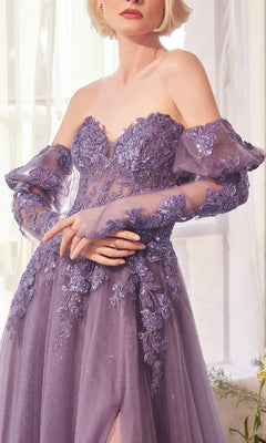 A woman stands indoors near a window wearing the Andrea & Leo A1398 Strapless Glitter Prom Gown.