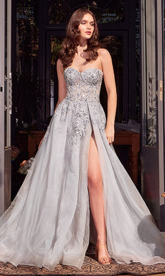 A woman stands in a doorway wearing the Strapless Prom Ball Gown: Andrea & Leo A1415, featuring light blue floral embroidery, a fitted bodice, and a high slit.
