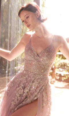 A woman in the Andrea & Leo A1416 Lace-Up Long A-Line Prom Dress stands by a window, looking down as natural light streams in from behind her.