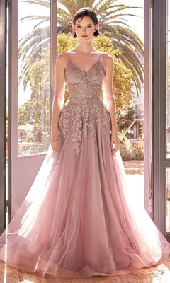 A woman stands in sunlight framed by open double doors and lush greenery, wearing the Andrea & Leo A1416 Lace-Up Long A-Line Prom Dress—a floor-length lilac gown with a sheer bodice and intricate floral embroidery.