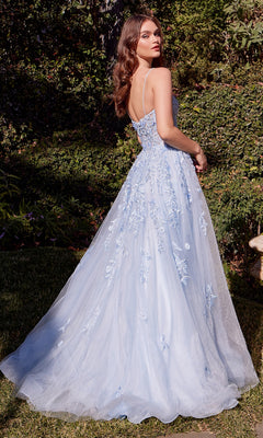 A woman stands outdoors in the Long Blue Prom Ball Gown: Andrea and Leo A1437, featuring floral embroidery and a tulle skirt, as she looks over her shoulder.
