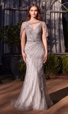 A woman stands outdoors in the Andrea and Leo A1443 long formal dress, featuring a beaded silver design with sheer, asymmetrical draped cape sleeves and a fitted embellished bodice.