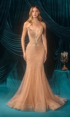 A woman stands before teal drapes wearing the nude Long Prom Dress: Andrea and Leo A1501—a strapless, form-fitting mermaid gown adorned with silver beading and a tulle skirt. A candelabra rests on a nearby table.