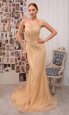 Wearing the Andrea & Leo A1519 long prom dress—an elegant, strapless gown with gold embellishments and a sweetheart neckline—a woman stands beside a blue and gold chair, with fashion sketches adorning the wall behind her.