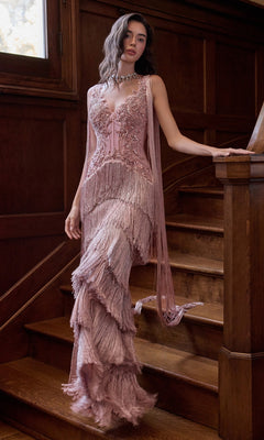 A woman stands on a wooden staircase wearing a mauve-colored Vintage-Inspired Prom Dress: Andrea & Leo A1529, featuring a beaded bodice, fringe detailing, and a layered floor-length skirt.