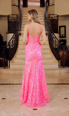 A woman stands with her back to the camera in front of a grand indoor staircase, wearing the Nox Anabel A1583, a long sequin-print prom dress with a sheer corset in bright pink.