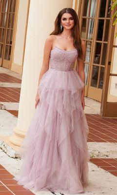 A woman stands outside a building wearing the Nox Anabel A1591 long prom dress—a strapless corset gown featuring a ruffled A-line skirt in light purple tulle with subtle sparkle details.