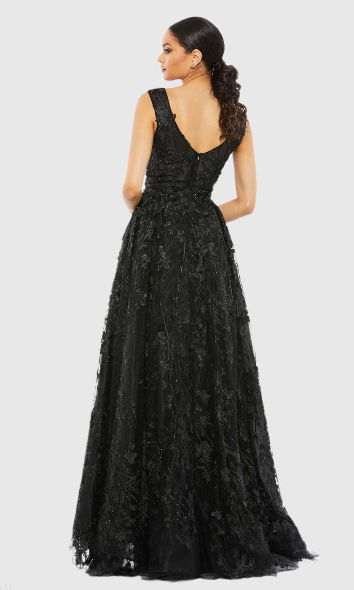 A woman faces away, wearing the Mac Duggal A20131 Embroidered Long Formal Dress—a floor-length, sleeveless black gown with a low back and delicate floral embroidery.