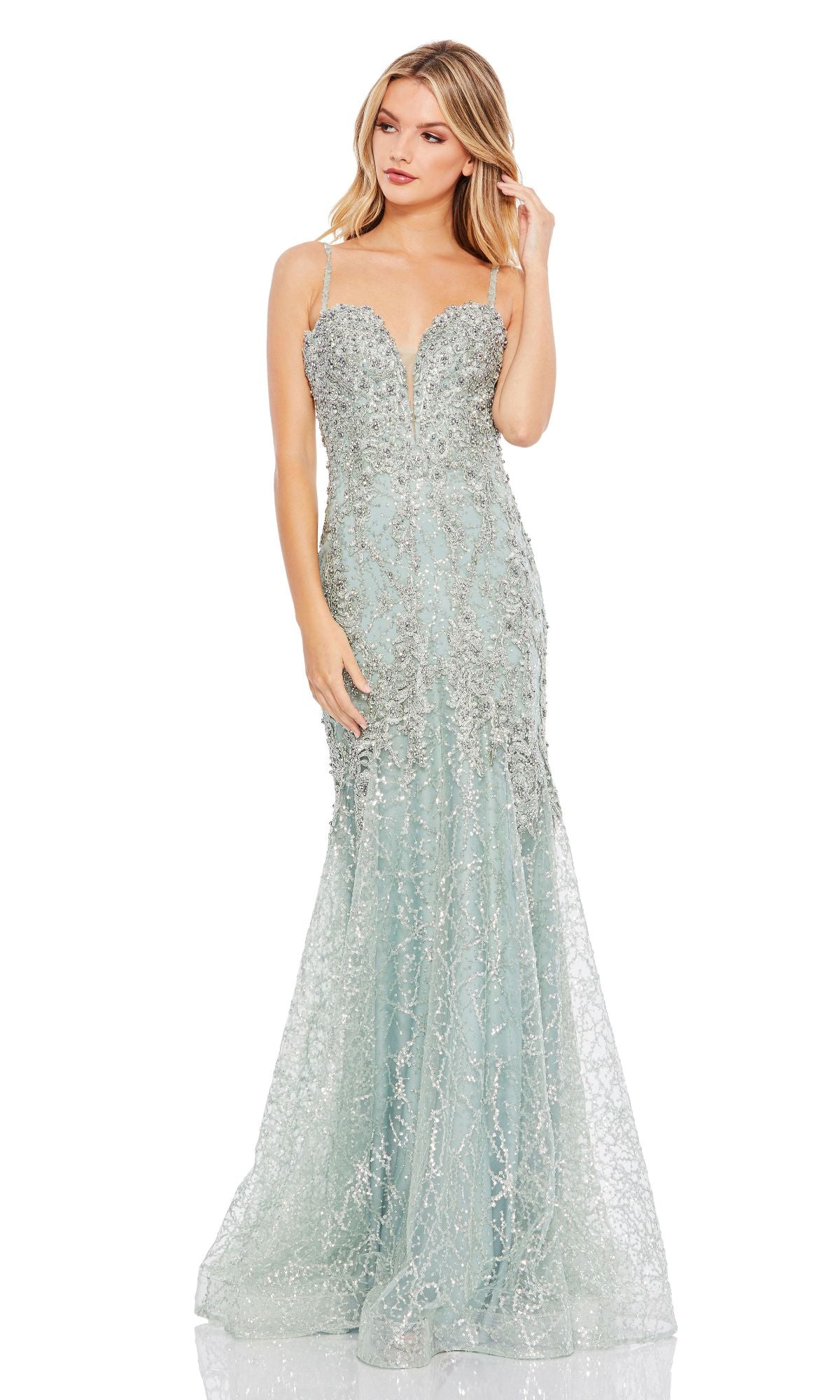 A woman stands against a white background wearing the Mint Green Glitter Prom Gown, Mac Duggal A20242—a floor-length mermaid dress with silver embellishments and thin straps.