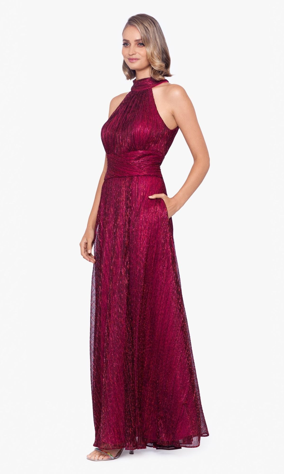 Woman wearing the Empire-Waist High-Neck Long Shimmer Prom Dress A24948 in dark red, featuring a sleeveless design, fitted waistband, and textured fabric, standing against a plain white background.