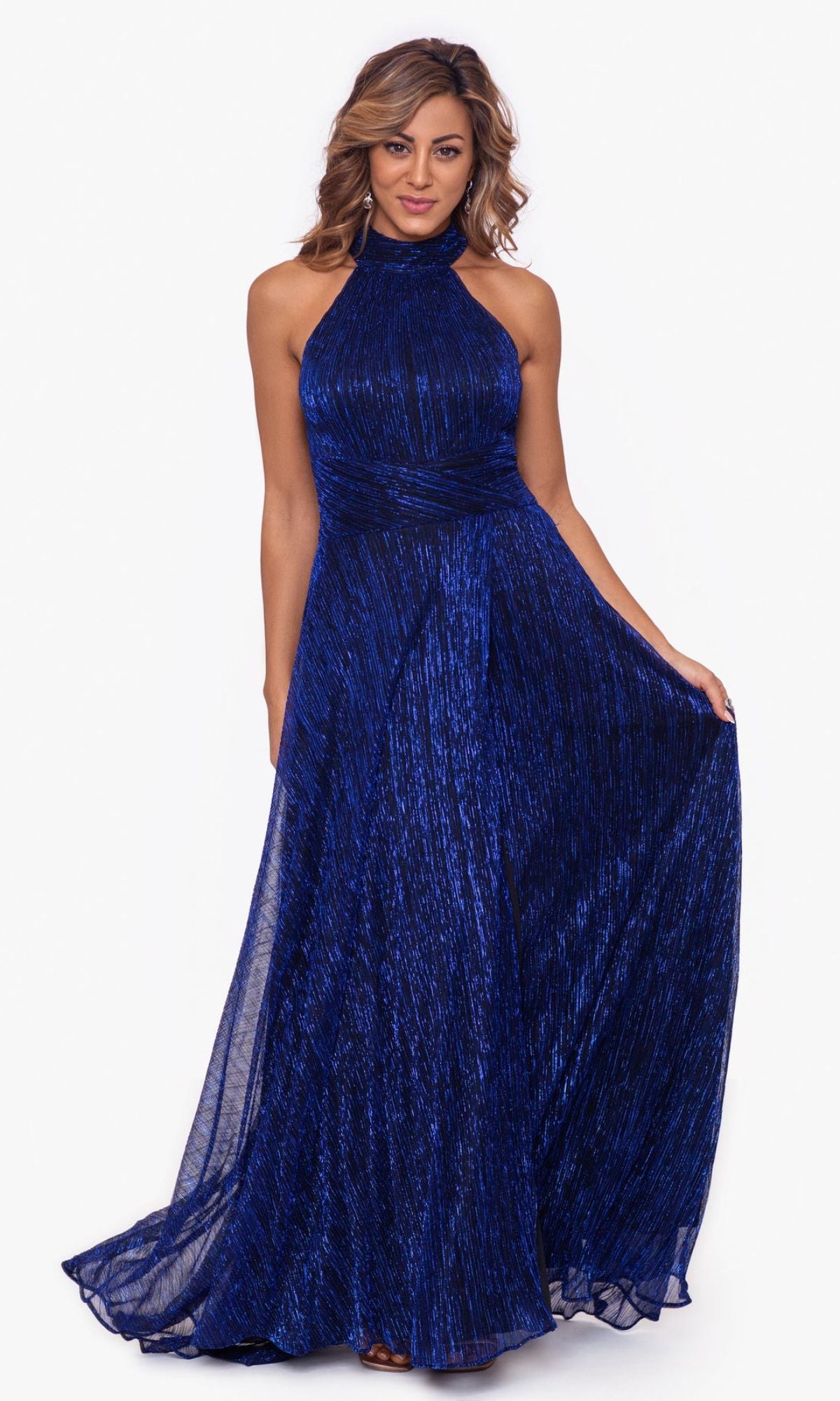 A woman models the Betsy and Adam Empire-Waist High-Neck Long Shimmer Prom Dress A24948, a sleeveless dark blue floor-length gown with a fitted bodice and slightly flared skirt, standing against a plain white background.
