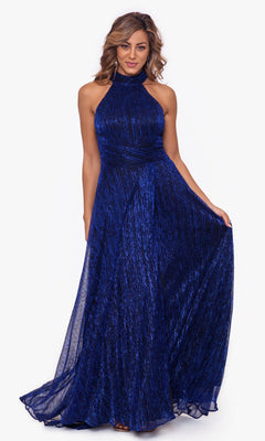 A woman models the Betsy and Adam Empire-Waist High-Neck Long Shimmer Prom Dress A24948, a sleeveless dark blue floor-length gown with a fitted bodice and slightly flared skirt, standing against a plain white background.