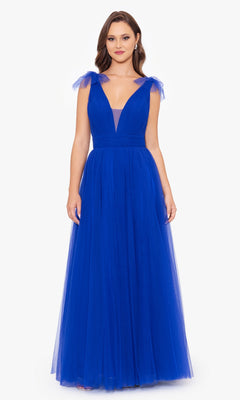 A woman in the Betsy & Adam Shoulder-Bow Long Prom Dress A26256—a sleeveless, royal blue, floor-length A-line gown with a deep V-neck and tulle shoulder bows—stands against a plain white background.