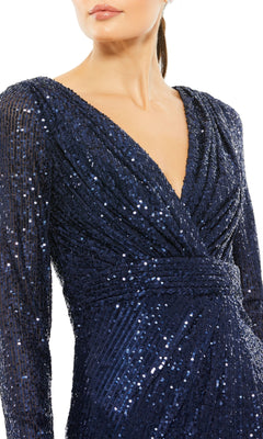 A woman wears the Mac Duggal 26555 Long Sleeve Sequin Party Dress in navy blue, with a deep V-neckline and gathered waist detail.