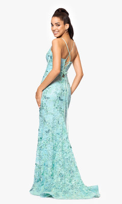 A woman stands smiling over her shoulder, wearing the Long Formal Dress: Betsy and Adam A26885—a light blue, floor-length lace gown with a corset bodice and open back.