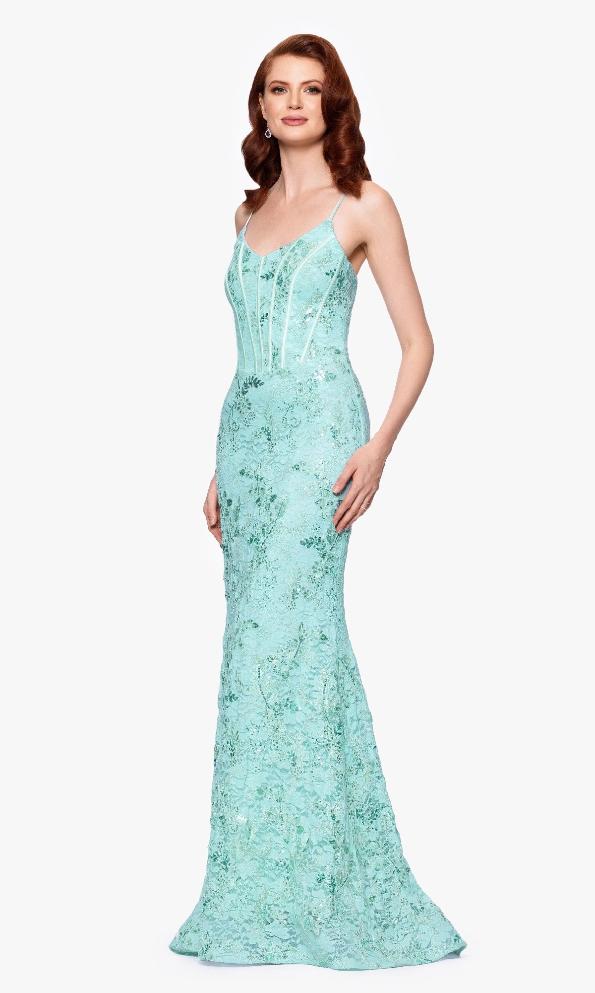 Woman wearing the Betsy and Adam A26885 long formal dress in light blue with a fitted corset bodice and lace details, standing against a plain white background.