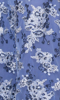 Close-up of the Betsy and Adam A26917 long formal dress, featuring light blue floral lace with detailed white and dark blue embroidery—perfect for elegant occasions.