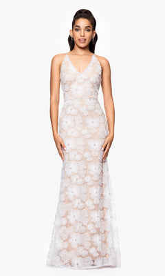 A woman stands facing forward against a plain white background, wearing the Betsy and Adam A26948 long formal dress featuring a white floral print, V-neckline, and adjustable shoulder straps.
