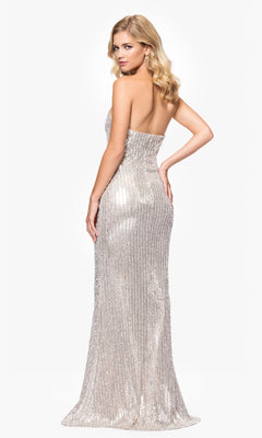 A woman in a strapless, floor-length Betsy & Adam A26952 Long Champagne Prom Dress stands looking over her shoulder against a plain white background.