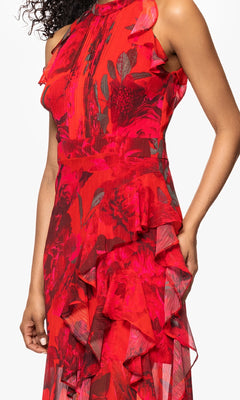 A person models the Betsy and Adam A26962 Floral-Print Red Formal Dress with ruffle details, standing against a plain white background.