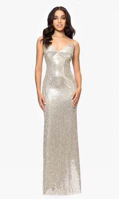 A woman stands against a white background wearing the Betsy and Adam A27009 long formal dress, featuring sleeveless styling, thin straps, a floor-length silver sequin design, and an elegant v-neckline.