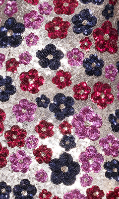 Close-up of the Betsy & Adam A27017 Floral-Sequin Long Prom Dress, featuring shiny red, purple, and dark blue sequin flowers on a silver background.