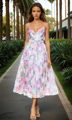 A woman in the Betsy & Adam A27054 Print Wedding Guest Dress with a sleeveless, pleated design and floral tones walks along a palm-lined sidewalk in an outdoor urban setting.