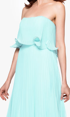A woman is wearing the Betsy & Adam A27098 Strapless Wedding Guest Dress, a light blue pleated formal dress featuring a ruffled top detail. Her head is out of frame.