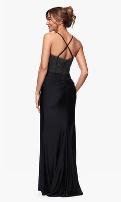 A woman is shown from behind wearing the Betsy and Adam A27256 long formal dress, which features a black fitted silhouette, an embellished corset bodice, crisscross straps, and an open back against a white background.