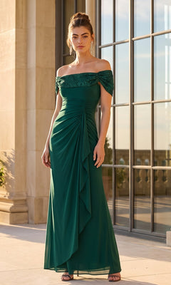 A woman wearing the Betsy & Adam A27436 long formal dress in pine, featuring an off-the-shoulder neckline and ruched detailing, standing on a terrace by large windows.