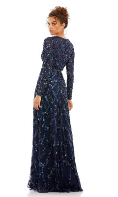 A woman faces away wearing the Mac Duggal 5496 Long Sleeve Sequin Formal Gown, a navy blue evening dress with intricate beaded details—an ideal choice for a mother of the bride.