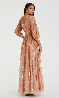 A woman stands slightly turned, wearing the Mac Duggal 5509—a long, formal rose gold evening gown with vertical stripes, sequins, and long sleeves.