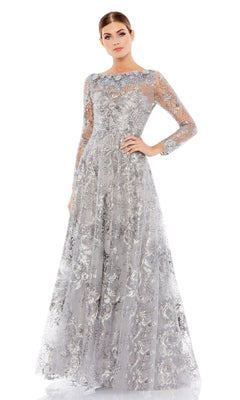 A woman poses with one hand on her hip in the Long Sleeve Long Formal Dress: Mac Duggal 67498, a floor-length silver evening gown with intricate floral lace patterns, set against a plain white background.