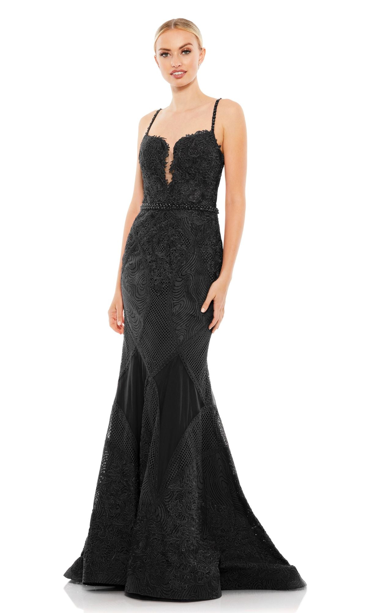 A woman models the Mac Duggal A79082, a fitted, floor-length black prom dress featuring embroidery, lace accents, thin straps, a sweetheart neckline, and a beaded waistline.