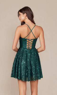 Woman in a short green Sequin Corset Homecoming Dress (Nox Anabel A843) with spaghetti straps and a lace-up back, standing against a plain beige background.