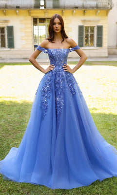 Woman in a blue evening gown standing in front of a building with green grass.