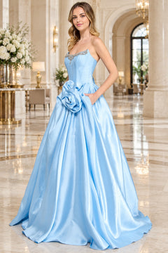 A light blue Corset Prom Ball Gown: Amelia Couture AL1401 strapless gown with a rhinestone-embellished neckline and a large fabric flower accent at the waist.