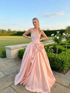 A person wears a rose-colored Amelia Couture AL1401 strapless corset prom ball gown with a beaded bodice and a large floral accent at the waist.