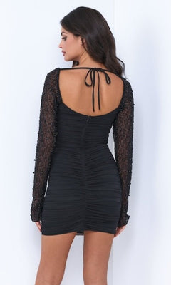 Woman wearing the Velvi Long-Sleeve Short Blue Party Dress Athena with a backless design and neck tie, standing against a white background and facing away from the camera.