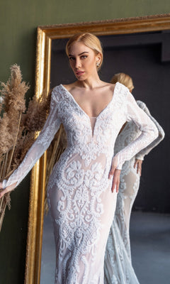 A woman in the Long Sleeve White Bridal Gown: Tina Holly BB021 stands before a large gold-framed mirror, with dried grasses beside her.